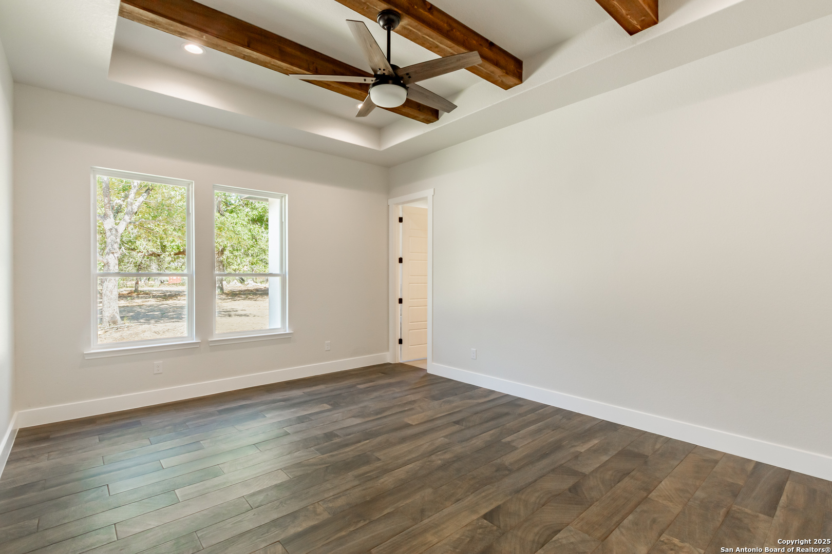 246 Timber Place La Vernia, TX 78121 - Photo 12 of 33 an empty room with wooden floor fan and windows