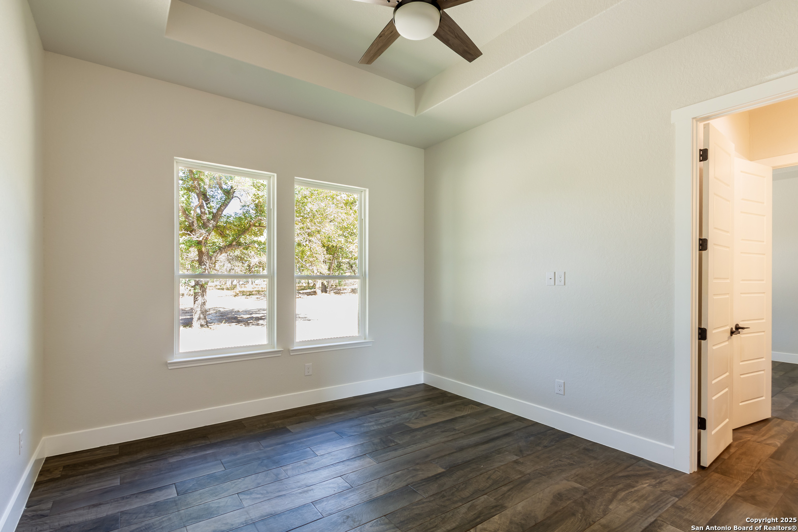246 Timber Place La Vernia, TX 78121 - Photo 21 of 33 an empty room with wooden floor chandelier fan and windows