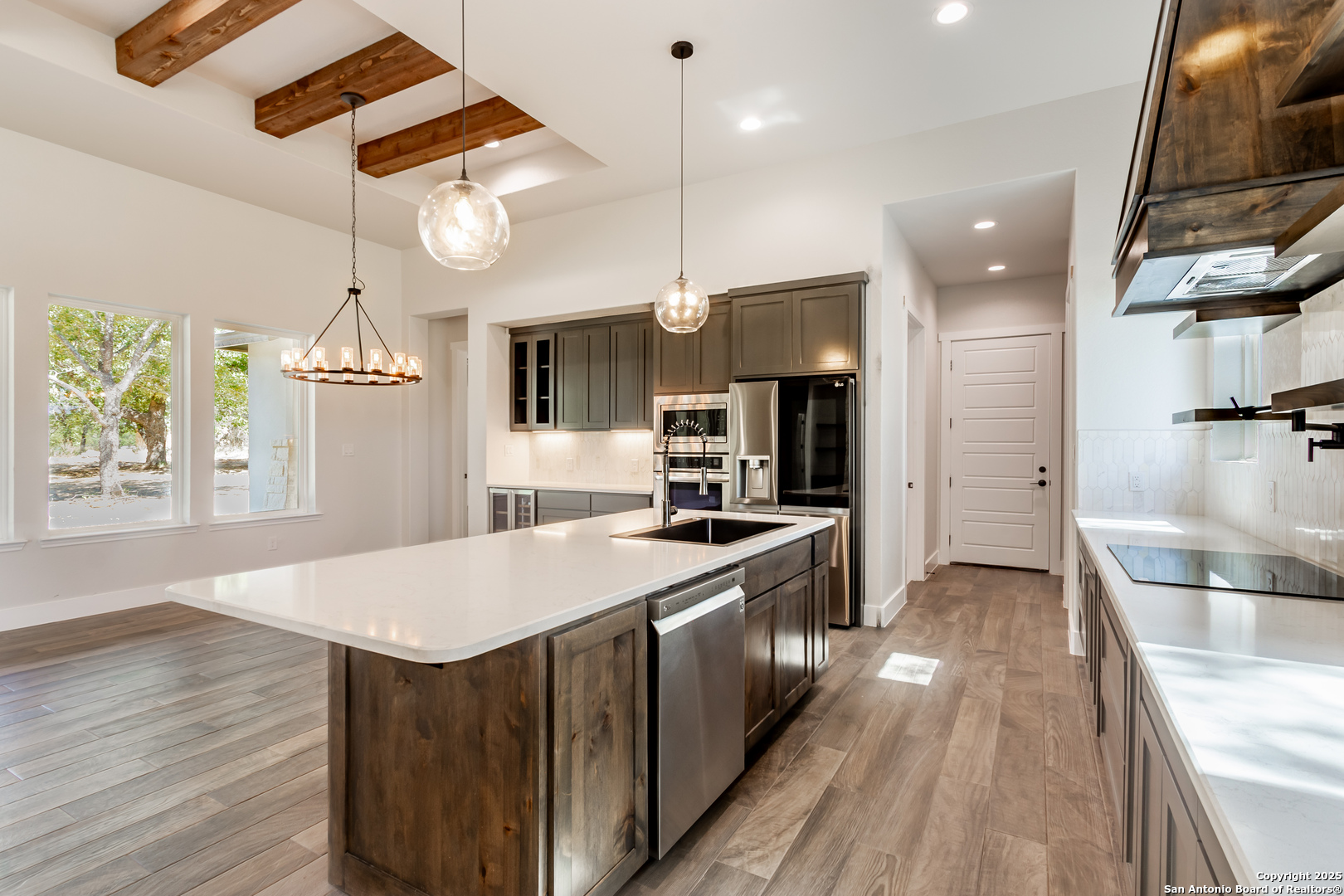 246 Timber Place La Vernia, TX 78121 - Photo 6 of 33 a kitchen with stainless steel appliances granite countertop a kitchen island a stove a refrigerator a oven and a sink with wooden floor
