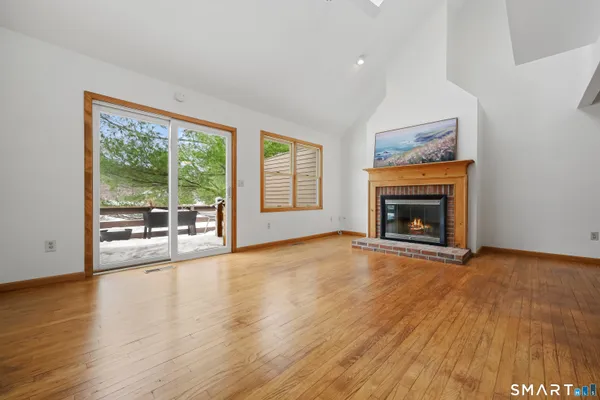 a view of empty room with wooden floor and fireplace