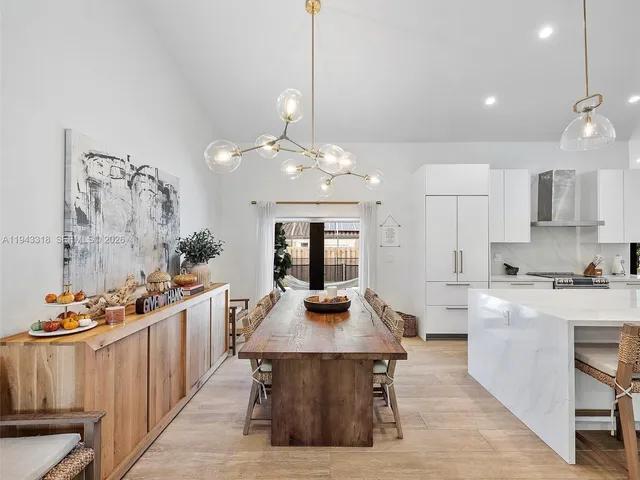 a kitchen with stainless steel appliances a dining table chairs stove and white cabinets