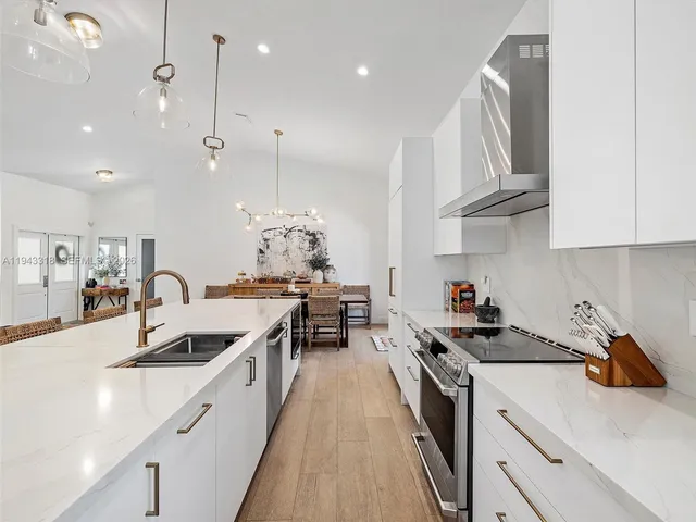 a kitchen with kitchen island granite countertop a sink a counter space appliances and cabinets