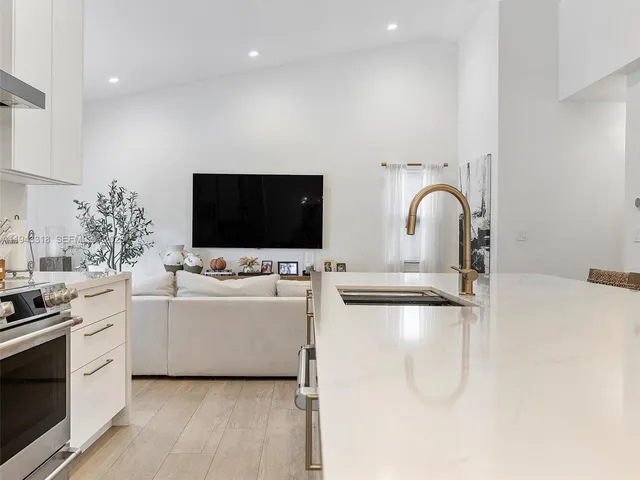 a living room with stainless steel appliances furniture and a flat screen tv