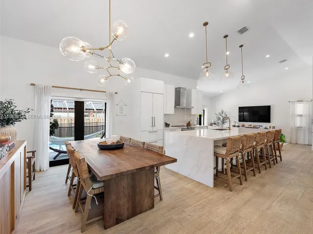 a kitchen with kitchen island a dining table and chairs