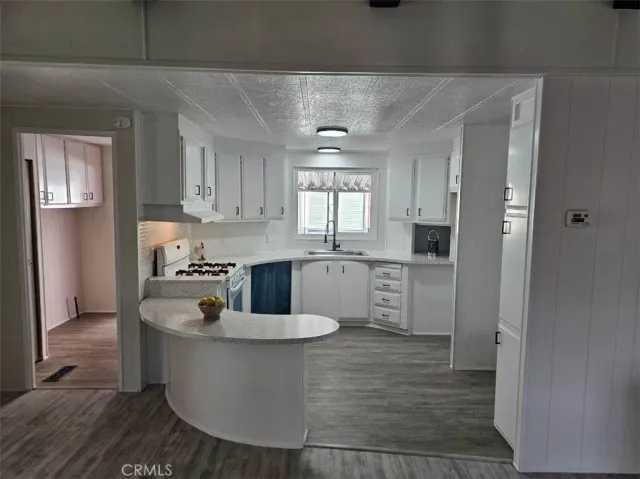 a large white kitchen with sink a window and stainless steel appliances