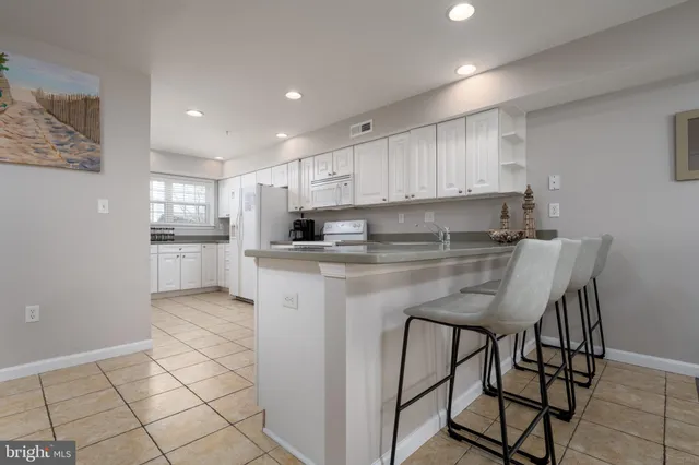 a kitchen with stainless steel appliances granite countertop a table chairs sink refrigerator and cabinets