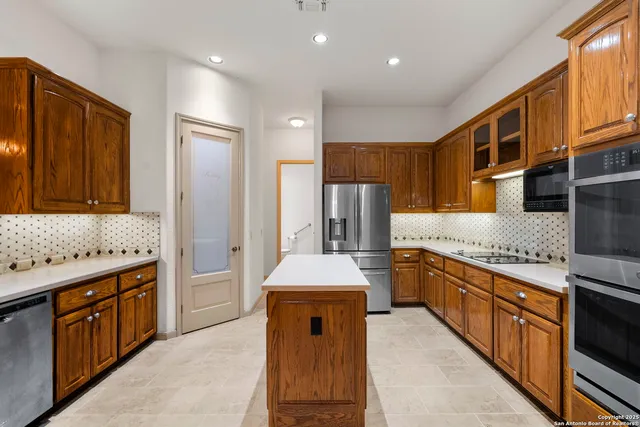 a kitchen with stainless steel appliances granite countertop a stove a sink dishwasher and a refrigerator with wooden cabinets