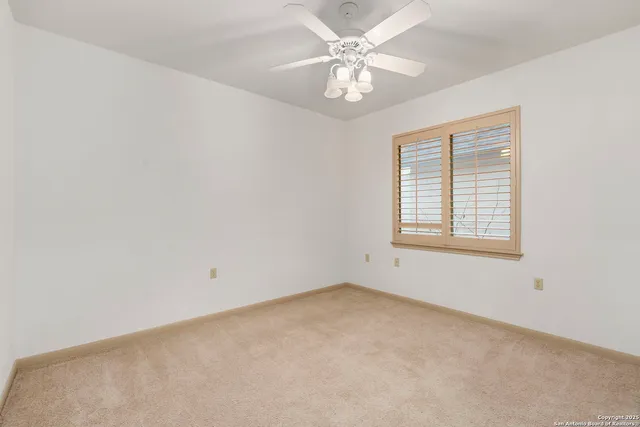 an empty room with a window and a fan