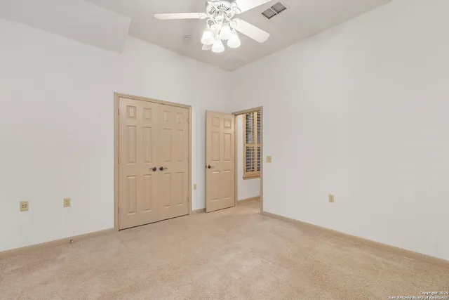 an empty room with a ceiling fan and a window