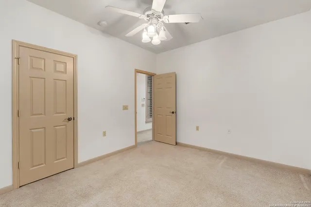 an empty room with chandelier fan and closet area