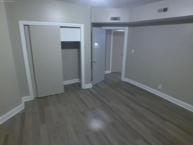 an empty room with wooden floor & closet area