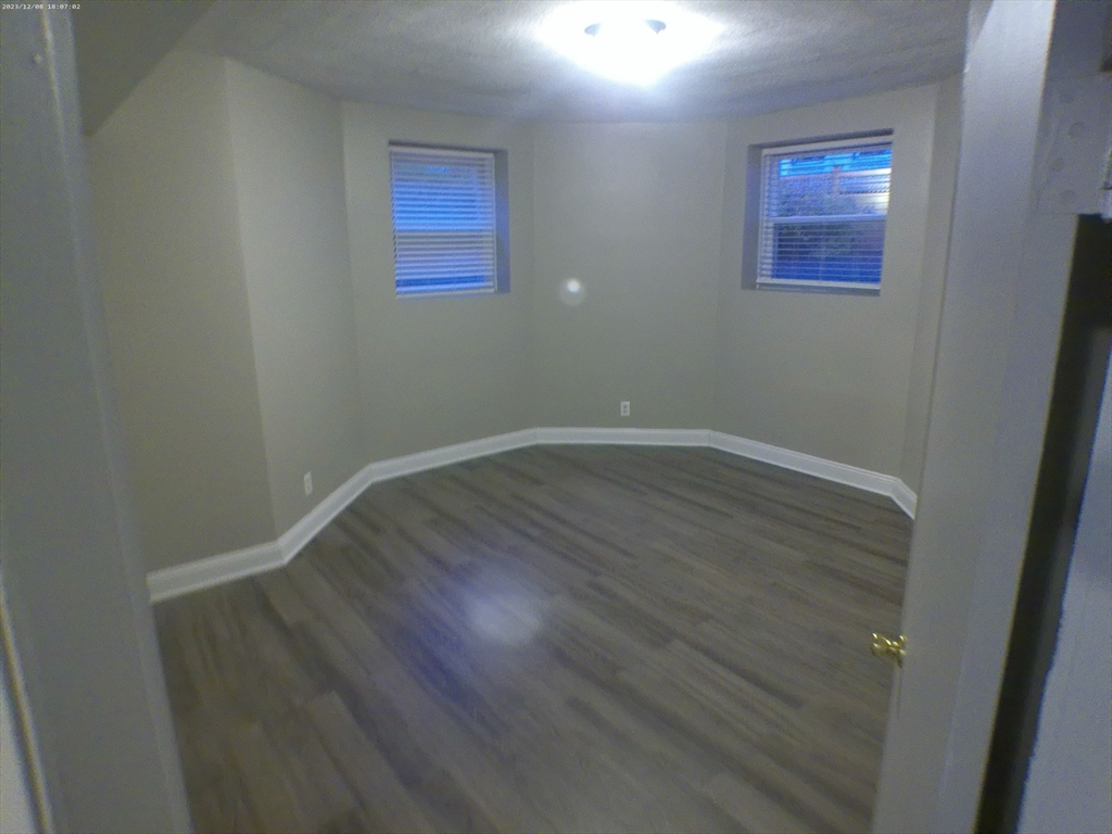 1862 Beacon Street, Unit 1B3 Brookline, MA 02445 - Photo 8 of 23 an empty room with wooden floor and windows
