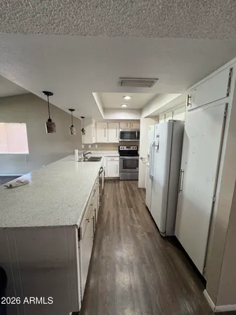 a kitchen with refrigerator and wooden floor
