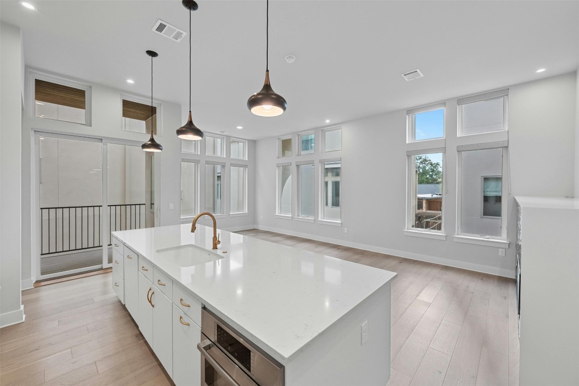a large white kitchen with a sink a center island and wooden floor