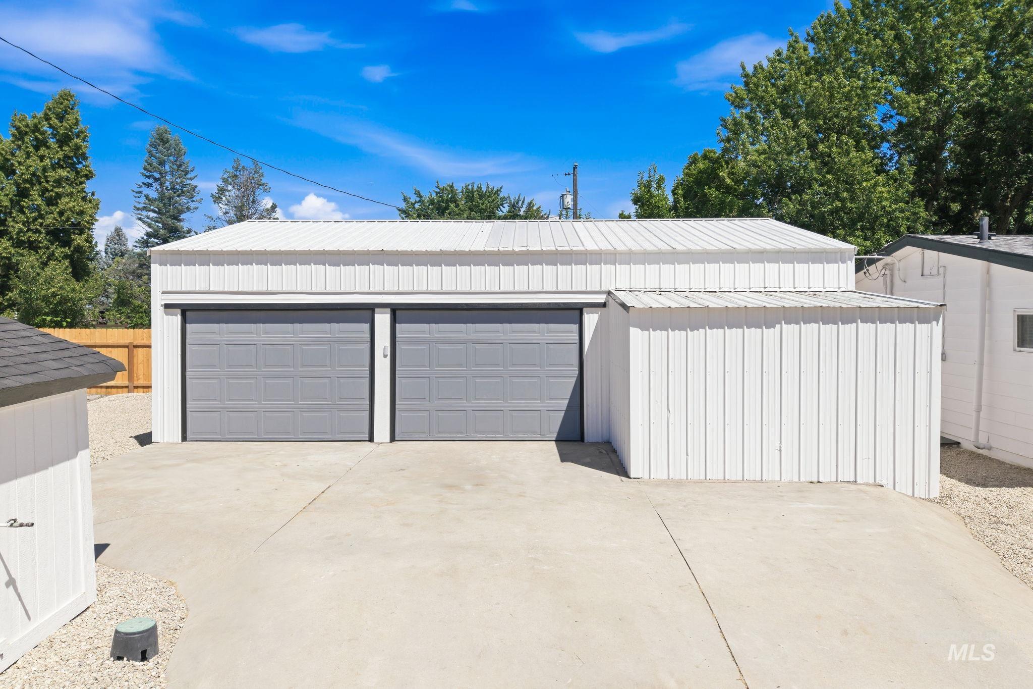 2152 Artesian Road Eagle, ID 83616 - Photo 39 of 50 Metal-sided garage structure featuring two gray panel garage doors, a corrugated metal roof, and an attached storage shed