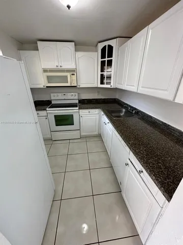 a kitchen with granite countertop a stove a sink and a microwave