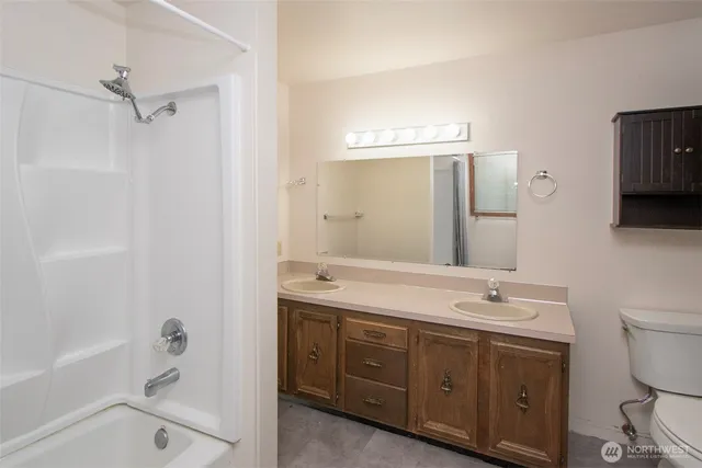 a spacious bathroom with a double vanity sink toilet mirror and bathtub