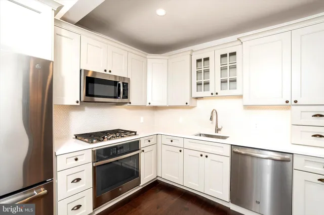 a kitchen with stainless steel appliances white cabinets a stove a sink a microwave and a window