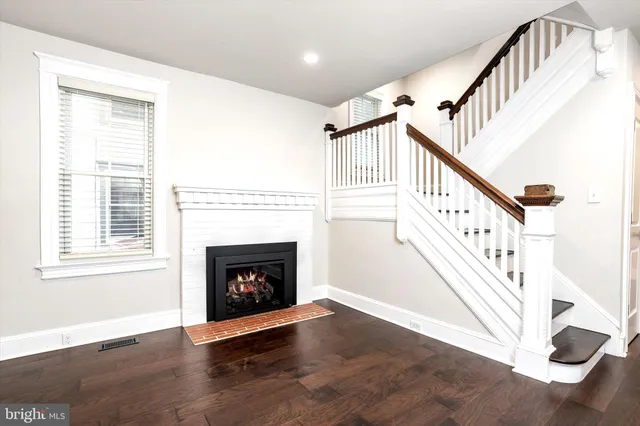 a view of an empty room with wooden floor fireplace and a window