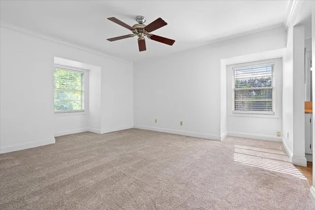 an empty room with windows and fan