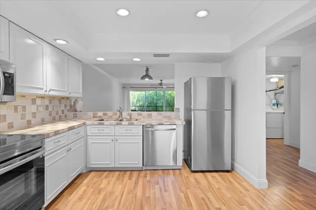 a kitchen with a refrigerator a sink dishwasher with a dining table and wooden floor