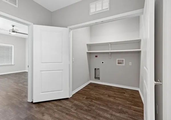 a view of an empty room with wooden floor and closet