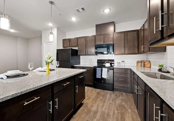 a kitchen with granite countertop a sink a counter top space stainless steel appliances and cabinets