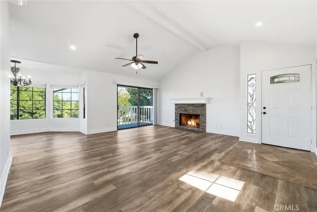 a view of an empty room with wooden floor fireplace and a window