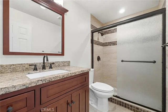 a bathroom with a granite countertop sink toilet and shower