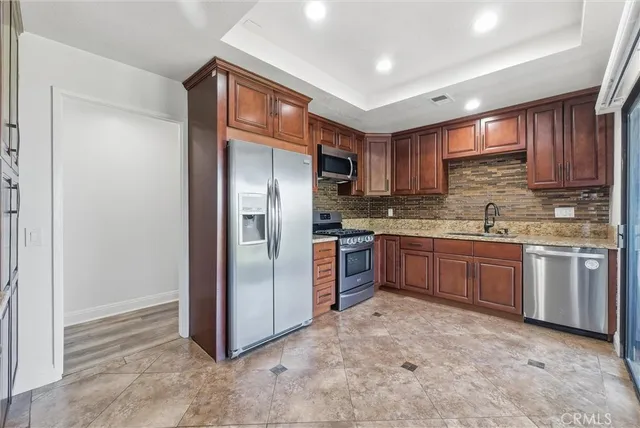 a kitchen with stainless steel appliances granite countertop a refrigerator and a stove top oven