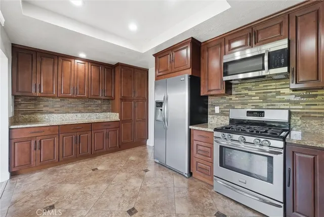a kitchen with stainless steel appliances granite countertop wooden cabinets stove top oven and sink