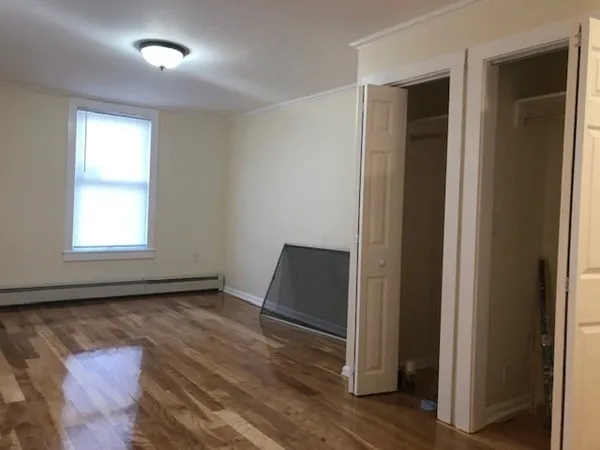 an empty room with wooden floor cabinet and windows