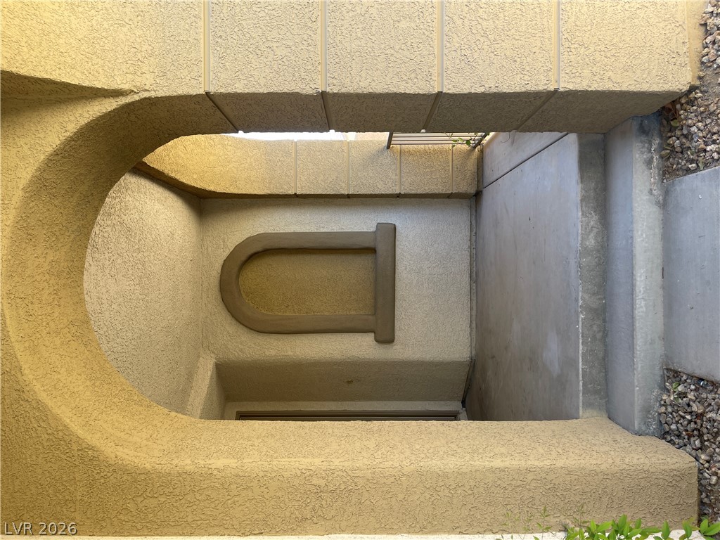 A stucco archway frames the recessed concrete entryway of this home.