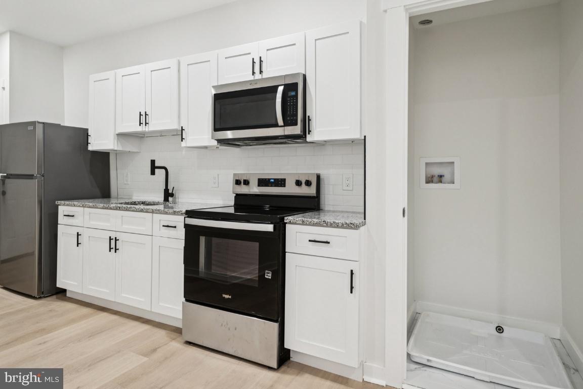 2330 Bryant Avenue Baltimore, MD 21217 - Photo 14 of 26 a kitchen with white cabinets and stainless steel appliances