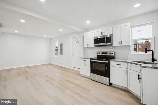 a kitchen with granite countertop a refrigerator and a stove top oven