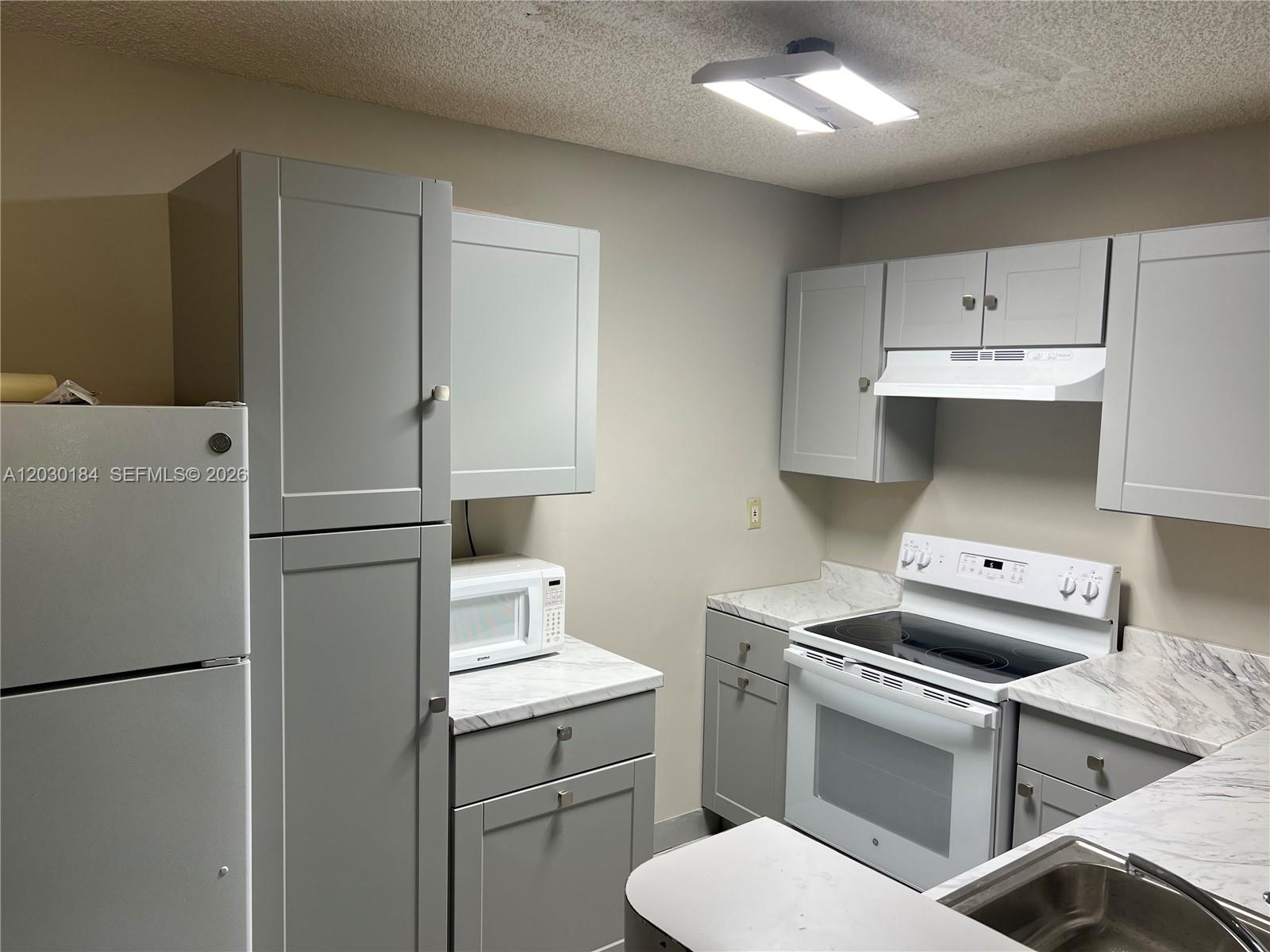 951 Lyons Road, Unit 6104 Coconut Creek, FL 33063 - Photo 8 of 18 a kitchen with a stove sink and refrigerator