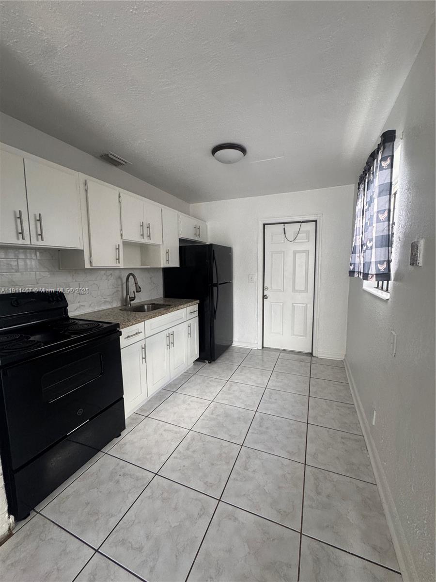 733 Northwest 4th Street, Unit 2 Hallandale Beach, FL 33009 - Photo 4 of 9 a kitchen with granite countertop a stove a sink and a refrigerator