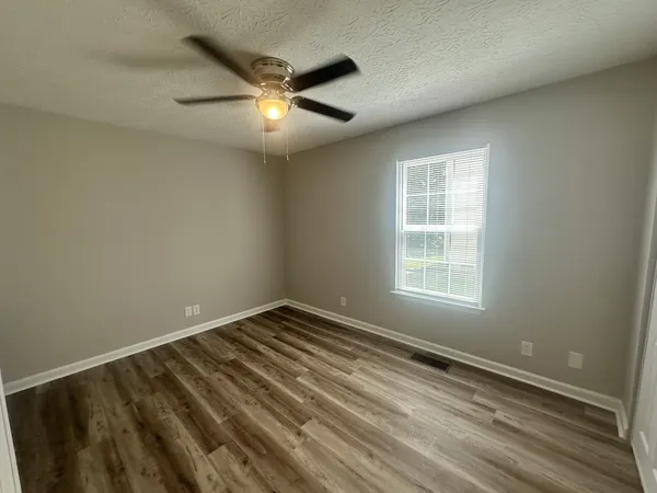 an empty room with a window and ceiling fan