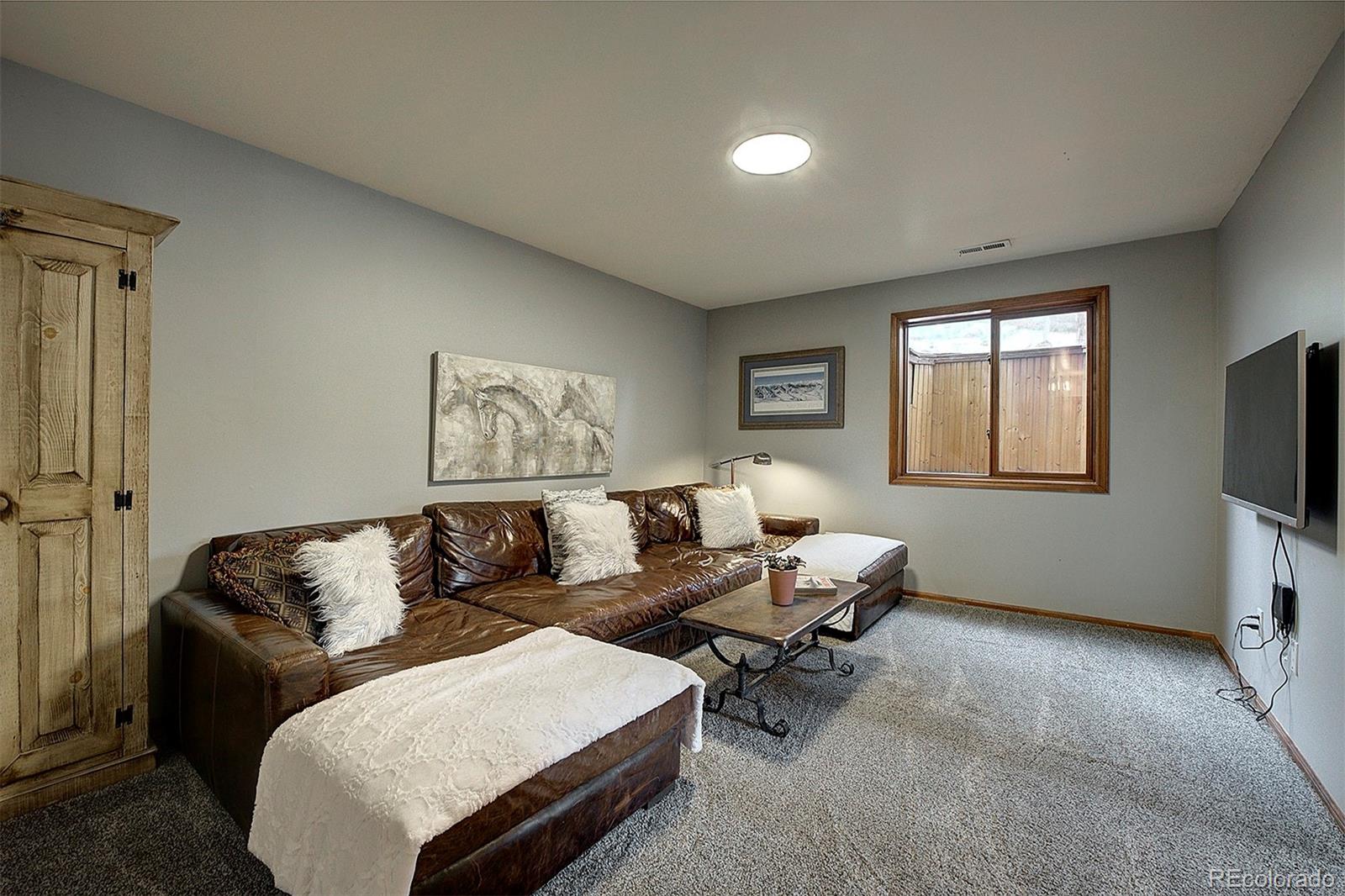 29659 Spruce Road Evergreen, CO 80439 - Photo 29 of 38 a living room with furniture and a flat screen tv
