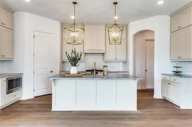a kitchen with stainless steel appliances granite countertop a sink stove and white cabinets with wooden floor