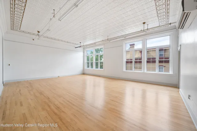 a view of an empty room with a window and wooden floor