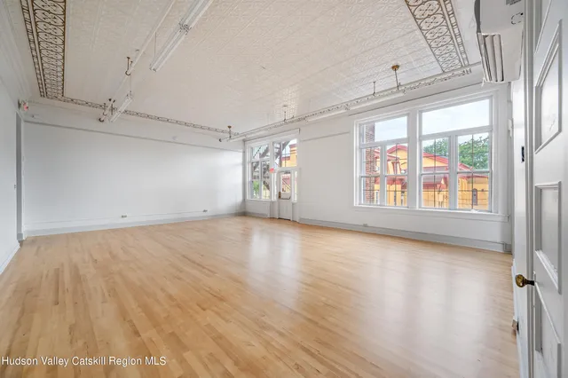 a view of an empty room with a window and wooden floor