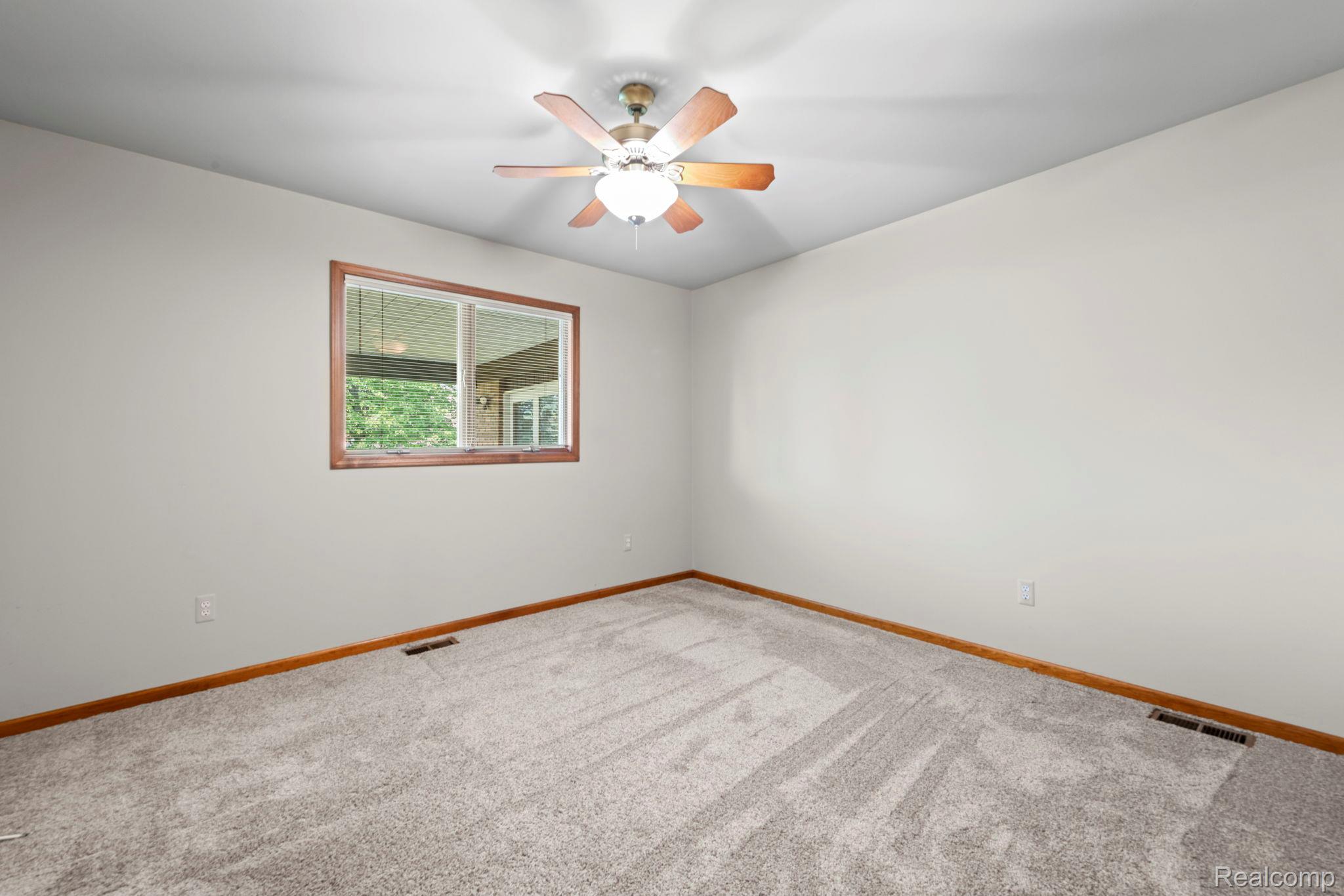 21580 Georgetown Road Trenton, MI 48183 - Photo 16 of 36 Carpeted interior space featuring a window with wood trim, a ceiling fan with light fixture, and wood baseboards