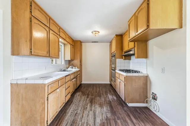 a kitchen with granite countertop a sink a counter top space and stainless steel appliances
