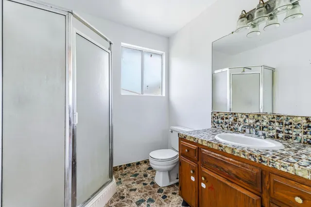 a bathroom with a granite countertop sink a toilet and a mirror