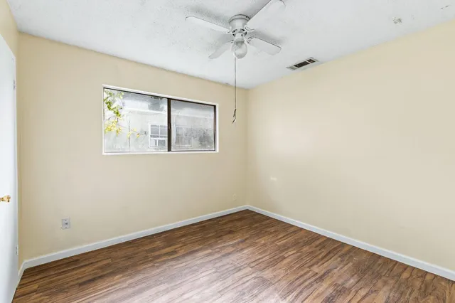 a view of empty room with wooden floor and fan
