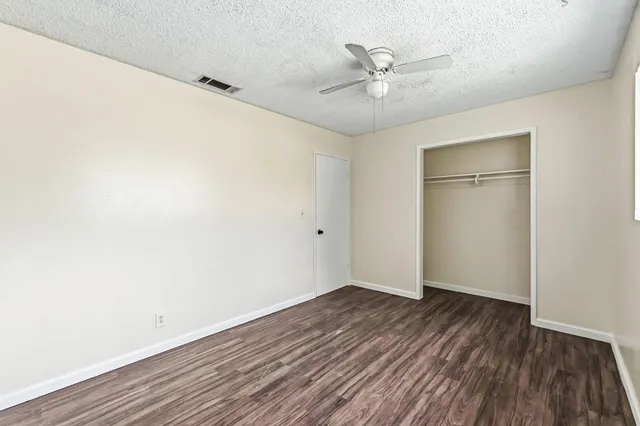 an empty room with a hardwood and ceiling fan