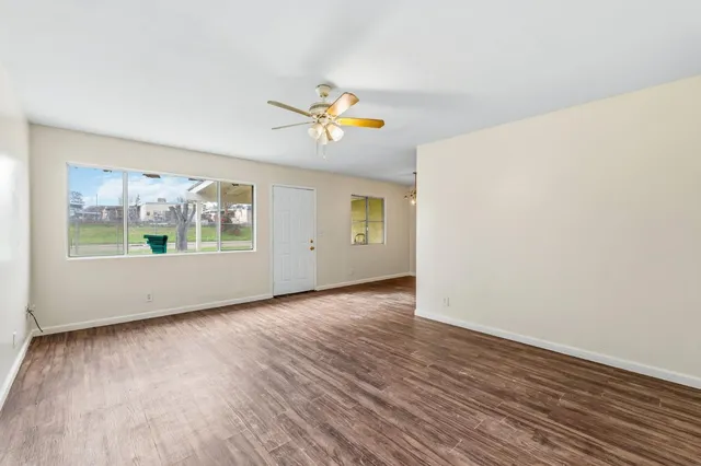 an empty room with wooden floor and windows