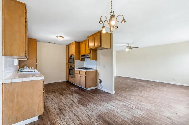 a kitchen with stainless steel appliances granite countertop a refrigerator a stove and a wooden floors