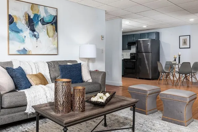 a living room with furniture a table and kitchen view